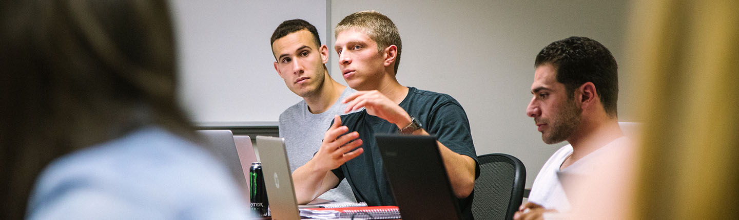 Students sitting in a classroom with their laptops.